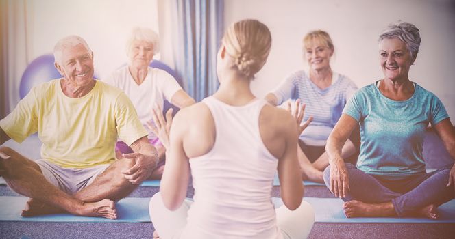 Instructor performing yoga with seniors during sports class