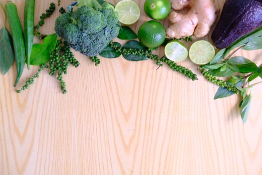 Fresh ripe green vegetables broccoli, ginger, lime, avocado, green pepper, Green okra and basil leaves on wooden background.  Organic vegetarian food ingredients vegetables  close up.