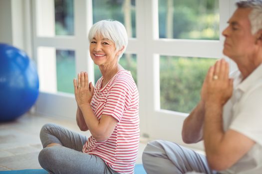Senior couple performing yoga on exercise mat at home