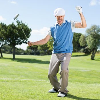 Excited golfer cheering on putting green on a sunny day at the golf course