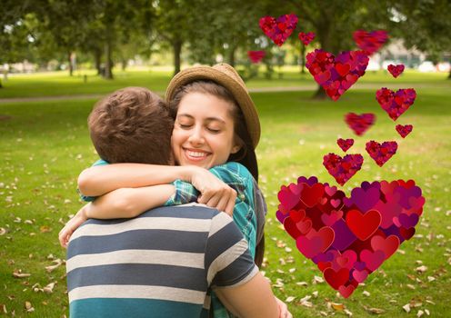 Composite image of romantic couple embracing each other in park with heart shapes