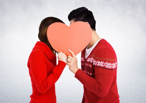 Romantic couple hiding their face behind heart against white background