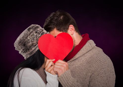Romantic couple holding heart shape and kissing each other against purple background
