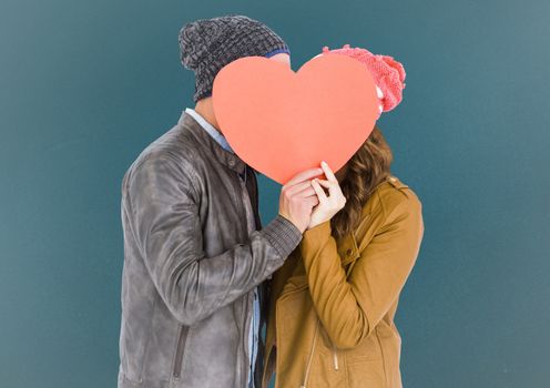 Romantic couple holding heart shape and kissing each other against blue background