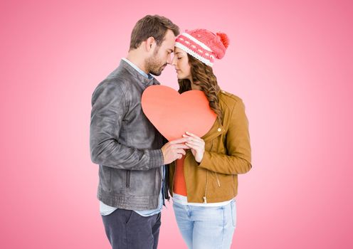 Romantic couple holding a red heart against pink background