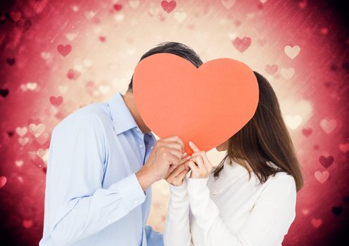 Composite image of romantic couple hiding their face behind heart