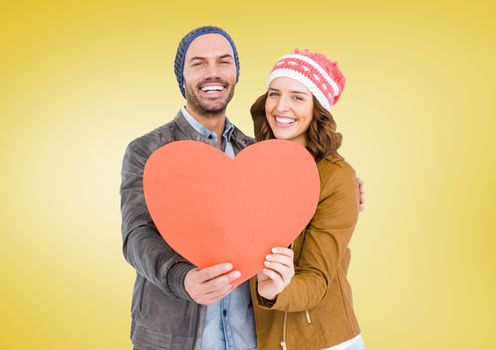Portrait of romantic couple holding heart against yellow background