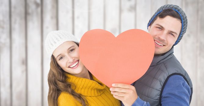 Portrait of romantic couple holding heart against wooden background