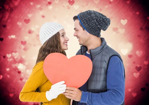 Romantic couple holding a heart against digitally generated heart background