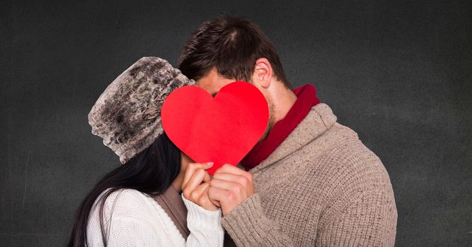 Romantic couple hiding their face behind heart against grey background
