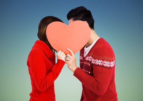 Romantic couple holding heart shape and kissing each other against blue background