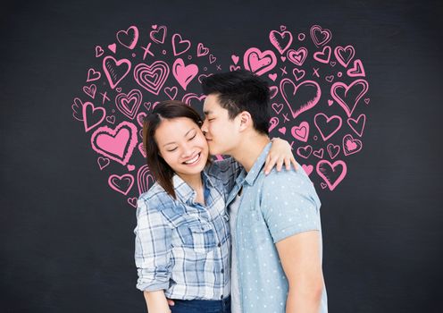 Romantic man kissing on the cheek of woman against black background with pink heart shapes
