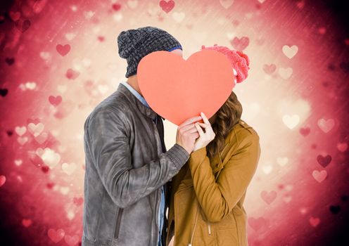 Composite image of romantic couple hiding their face behind heart