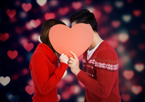 Romantic couple hiding their face behind heart against digitally generated background