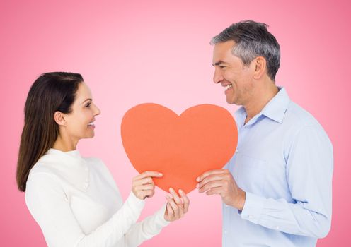 Romantic couple holding heart shape against pink background