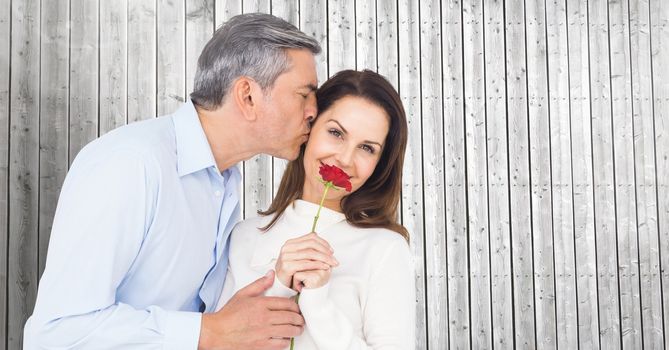 Romantic man kissing on the cheek of woman against wooden background