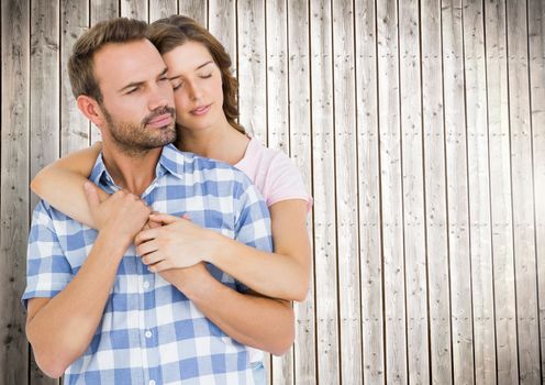 Romantic couple embracing in front of wooden background