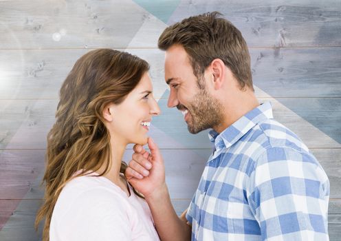 Romantic couple looking at each other and smiling against wooden background