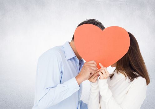 Romantic couple holding heart shape and kissing each other against grey background
