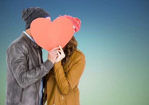 Romantic couple hiding their face behind heart against blue background