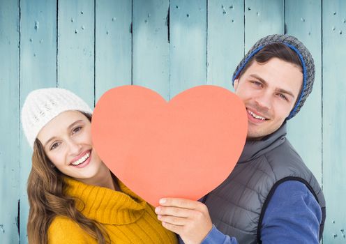 Romantic couple holding a heart against wooden background