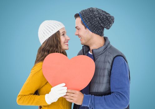 Romantic couple holding heart shape against blue background