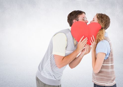 Romantic couple kissing behind heart against white background