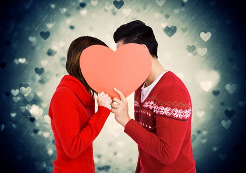 Romantic couple holding heart shape and kissing each other against digitally generated background