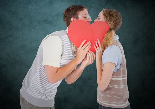 Romantic couple kissing behind heart against teal background