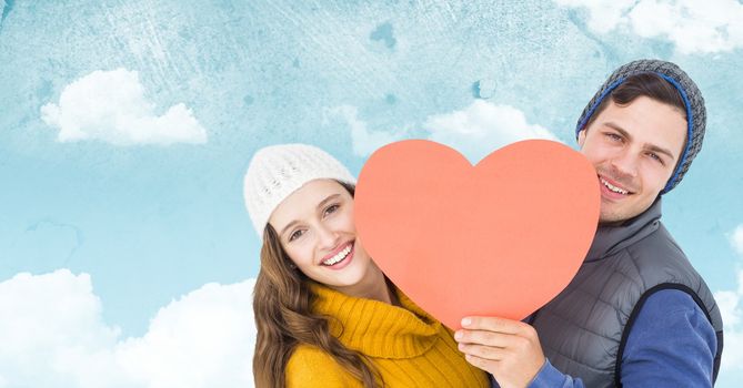 Portrait of romantic couple holding heart against digitally composite sky background