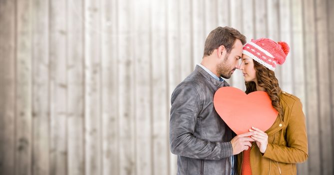 Romantic couple holding a heart against wooden background
