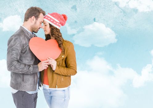 Romantic couple holding heart against digitally generated sky background