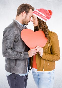 Romantic couple with face to face holding heart against white background