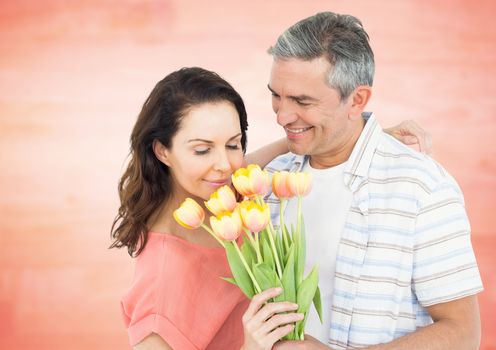 Romantic couple smelling roses against orange background