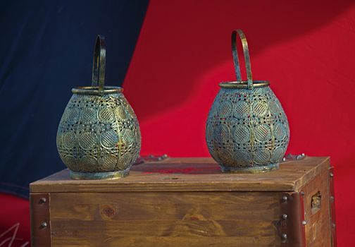 Two medieval pots standing on wooden chest in front of red and blue fabric