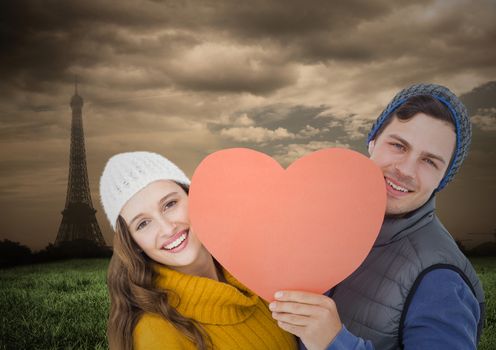 Portrait of romantic couple holding heart against digitally generated eifel tower background