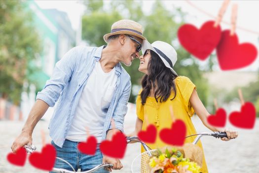 Romantic couple on bicycle looking face to face against hearts hanging on a line