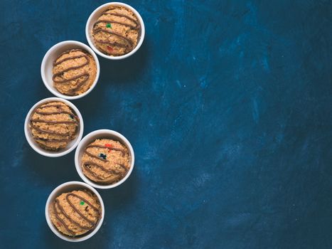 Safe-to-eat raw monster cookie dough in small portion bowl on blue background. Ideas and recipes for kids and toddlers meal. Top view or flat-lay. Copy space for text.