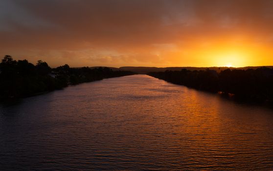 Scenic views of Nepean River Penrith in pretty sunset colours and a backdrop of silhouetted mountains in the distance.
