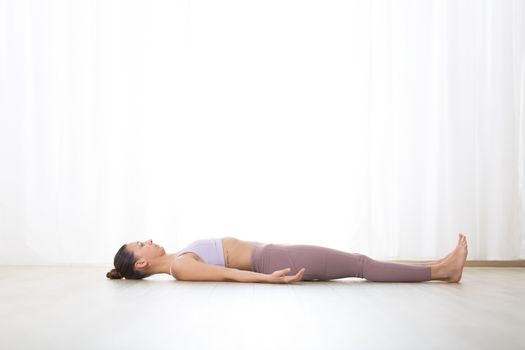 Portrait of gorgeous active sporty young woman practicing breathing exercises in yoga studio. Healthy active lifestyle, working out indoors in gym.