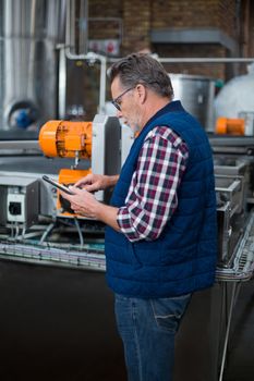 Factory worker working on digital tablet at drinks production plant