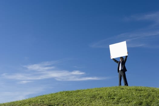 Businessman holding a placard on the top of a hill themes of placard advertisement copy space