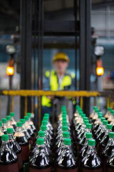 Factory worker driving forklift in drinks production factory