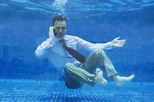 Caucasian businessman talking on a mobile phone underwater themes of danger helpless challenge