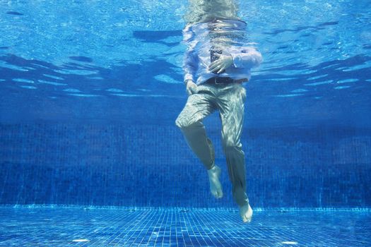 Low angle of businessman's legs underwater themes of danger helpless challenge