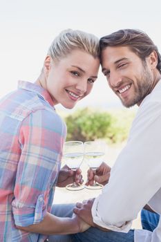 Happy couple smiling at camera holding wine glasses at home in the garden