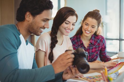 Fashion designers looking at photographs in digital camera at office