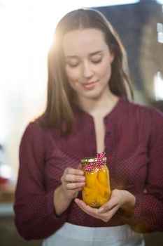 Shop assistant holding a jar of pickle in grocery shop