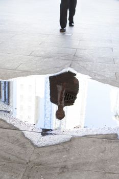 Caucasian businessman leaving the office stepping over a puddle on his way home themes of obstacle puddle the way ahead best foot forward