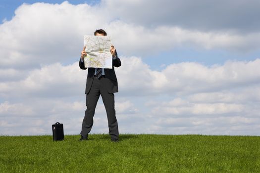 Caucasian businessman reading a map in a field themes of lost explore guidance